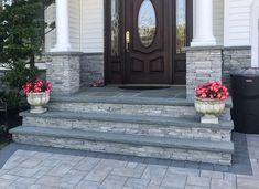 two planters with flowers are sitting on the steps in front of a door that is open