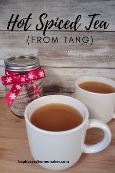 two mugs of hot spiced tea sit on a table next to a jar