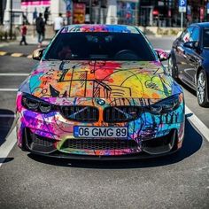 a colorful car is parked on the side of the road with graffiti all over it