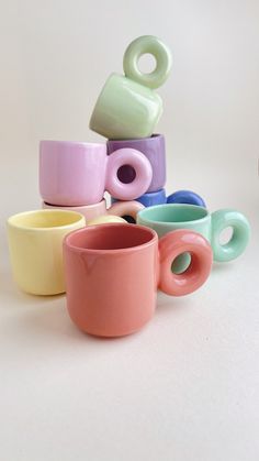 there are many different colored cups on the white table top, and one has a doughnut in it