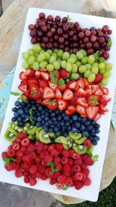 grapes, strawberries, and kiwis are arranged on a platter to be eaten