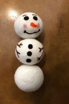 two snowmen sitting on top of each other in front of a brown tablecloth