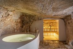 a bath room with a large white tub next to a stone wall