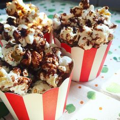 two red and white striped paper cups filled with chocolate covered caramel popcorn kernels