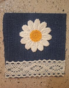 a crocheted doily with a white flower on it sitting on the ground