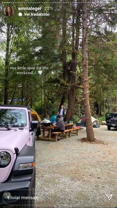 a pink jeep parked in front of a forest filled with trees and people sitting at picnic tables