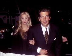 a man in a suit and tie standing next to a woman wearing a black dress