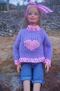 the doll is wearing a purple sweater with hearts on it's chest and blue jeans