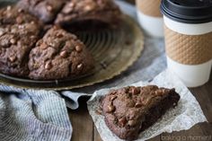 two chocolate muffins are on a plate next to a cup of coffee and a napkin