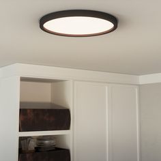 a bathroom with white cabinets and a round light fixture above the toilet paper dispenser