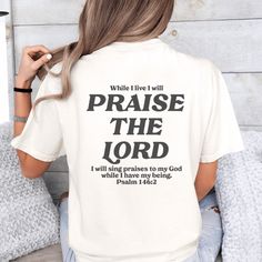 This Praise the Lord t-shirt with Psalm 146:2 Bible verse on the back is a great way to proclaim your faith! Trendy Christian graphic tees like this Praise The Lord shirt can make a bold statement in sharing your love for the Lord and serve as a reminder to Praise Him in all you do! Plus, it's a great way to share God's word and plant seeds of faith anywhere you go! This cute Christian t-shirt is versatile to create a cool Christian street style with sweats or joggers. Or size up and pair it wit Inspirational Crew Neck T-shirt With Lettering, Inspirational Lettering Crew Neck T-shirt, Bible Verse Shirts, God Shirts, Worship Night, Christian Graphics, Christian Graphic Tees, Bible Shirts, Praise Him