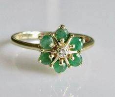 This is a 9ct yellow gold emerald diamond round flower cluster ring. The round flower cluster measures 10mm by 10mm and the band width is 2mm. UK size P or a US size 7 1/2 Weight 1.8 grams. Hallmarked 375 for 9ct gold. Emerald Flower Ring, Gold And Emerald Ring, Enchanting Rings, Channel Ring, Flower Cluster Ring, Flower Cluster, Ring Flower, Round Flower, Shiny Things