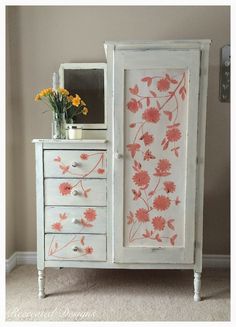 a white cabinet with flowers painted on the doors and drawers is next to a mirror