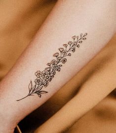 a small flower tattoo on the left forearm and foot, with tiny flowers growing out of it