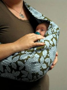 a woman holding a baby wrapped in a wrap