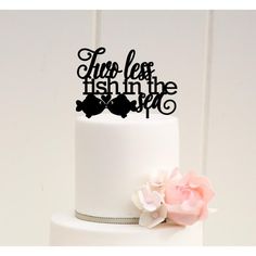 there is a white cake with black lettering on it and pink flowers in the foreground