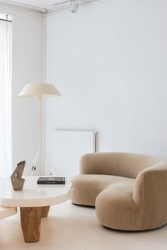 a living room filled with furniture and a lamp on top of a white table in front of a window