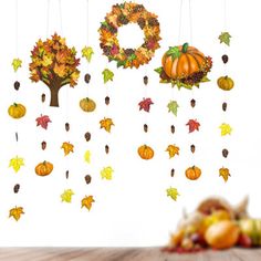 an autumn scene with fall leaves and pumpkins hanging from the ceiling next to a wooden table