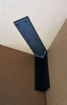 the corner of a cardboard box with a black metal object on it's side