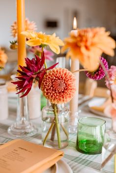 the table is set with flowers and candles for an elegant dinner or party setting in shades of orange, pink, yellow and green