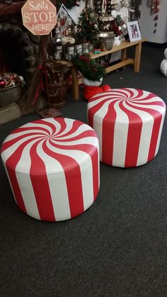 two red and white striped stools sitting in front of a christmas tree