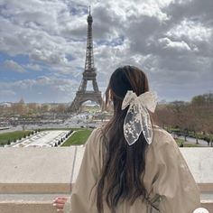 a woman standing in front of the eiffel tower with her back to the camera