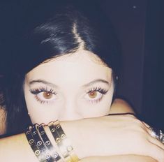 a close up of a person with two bracelets on their arms and one arm wrapped around her face