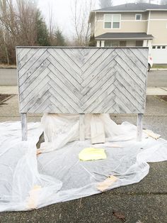 a bed frame is covered with plastic in front of a house that has been boarded up