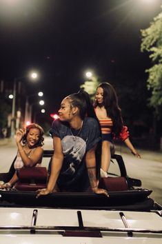 three people sitting in the back of a car at night