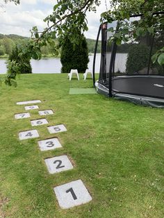 an outdoor area with numbered numbers on the grass and a boat in the water behind it