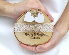 the bride and groom are holding their wedding rings on top of a slice of wood