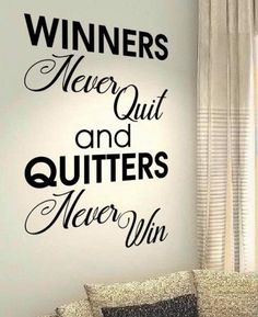 a living room with a couch, window and wall decal that says winners never quit and quits never win