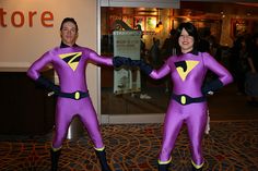 two people in purple costumes standing next to each other with their hands on their hips