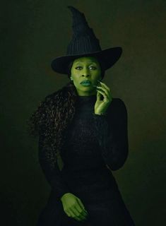 a woman with green makeup wearing a witches hat