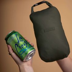 a woman holding up a can of la croixe in front of an insulated pouch