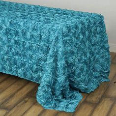 a bed covered in a blue bedspread on top of a hard wood floor