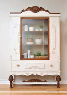 a white china cabinet with plants in it