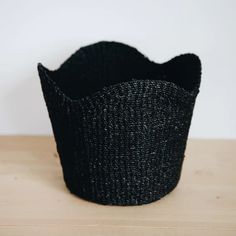 a black basket sitting on top of a wooden table