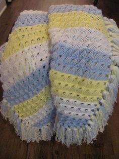 a crocheted blanket sitting on top of a wooden floor next to a rug