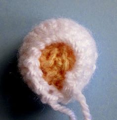 a white crocheted object on a blue surface with a string attached to it