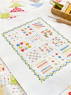 a table topped with lots of different types of quilts and sewing needles on top of it