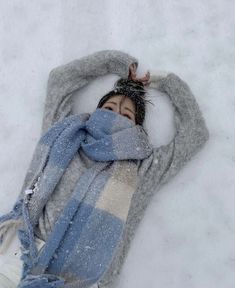 a woman is laying in the snow wearing a scarf