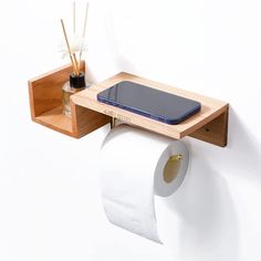 a cell phone is sitting on top of a toilet paper holder that holds two rolls of toilet paper