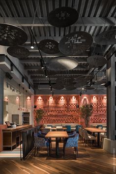 an empty restaurant with wooden tables and blue chairs in the center, surrounded by hanging lights