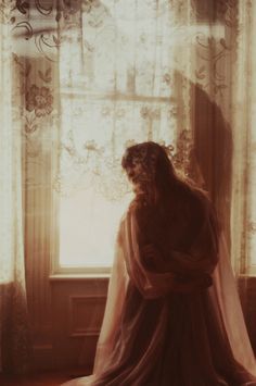 a woman standing in front of a window with her hands on her hips and wearing a veil