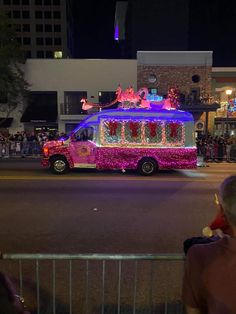 a truck with decorations on it driving down the street in front of a crowd at night