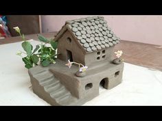 a clay house sitting on top of a table next to a potted green plant