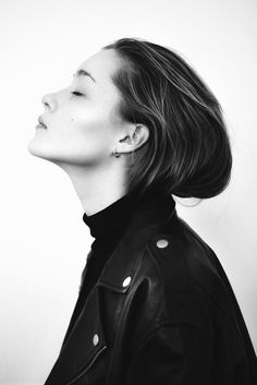 black and white photograph of woman in leather jacket looking up to the sky with her eyes closed