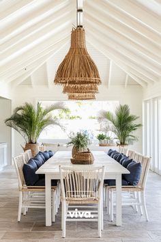 a dining room table with blue cushions under a hanging basket and some potted plants