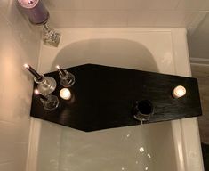 a bathtub with two candles on the side and soap dispenser above it